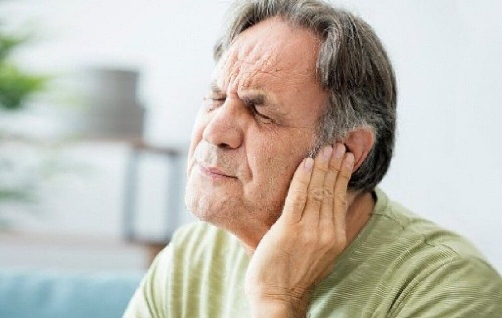 A man pressing his ears during tinnitus